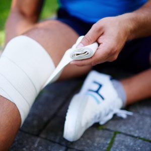 Close-up of male bandaging his leg