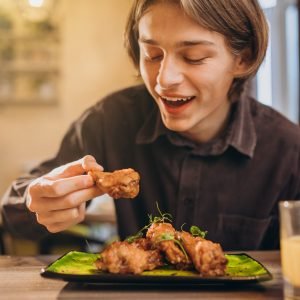 Man eating fried chicken with sauce in a cafe