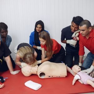 People are practicing medicine.Men and women are learning how to properly provide first aid.