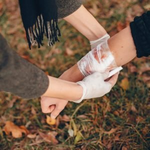 Providing first aid in the park. Man bandaged injured arm. Guy helps a friend.